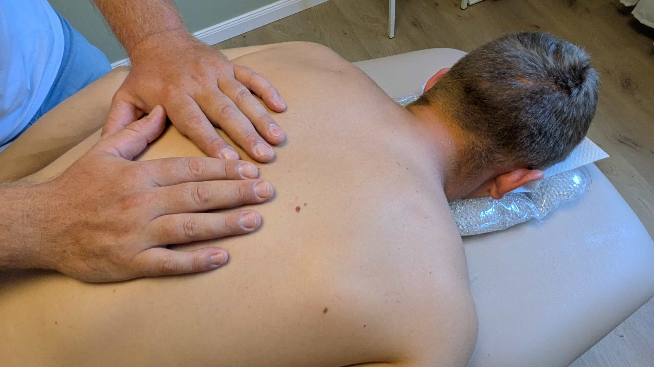 Physiotherapie in Mainz-Drais, Rückenmassage bei Patient auf Behandlungsliege.